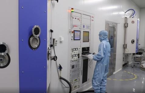 Cleanroom technician operating optical thin-film coating equipment